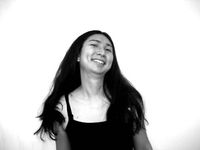 Black and white photo of Gein Wong. They have long black hair, are of Asian descent, and appear to be in motion.